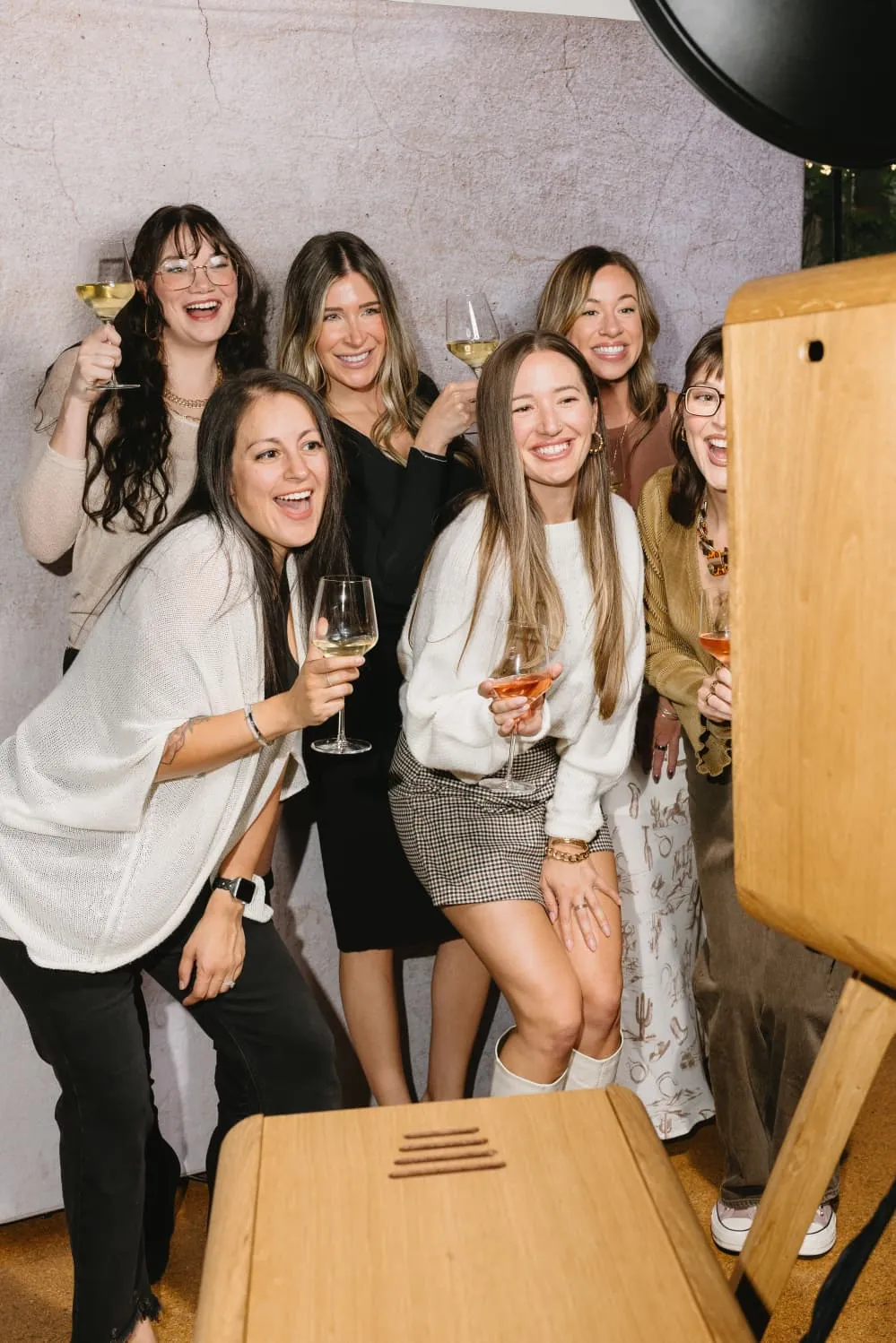 A group of attendees with drinks laughing together at the photo booth
