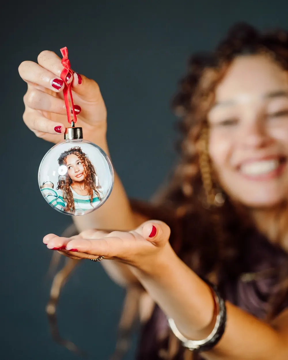 A guest holding a clear Christmas bauble with her portrait inside