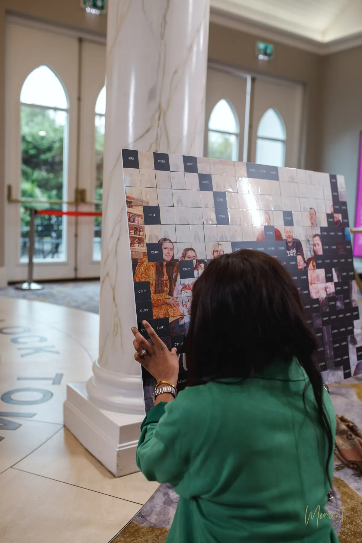 A guest placing her portrait tile onto the photo mosaic board