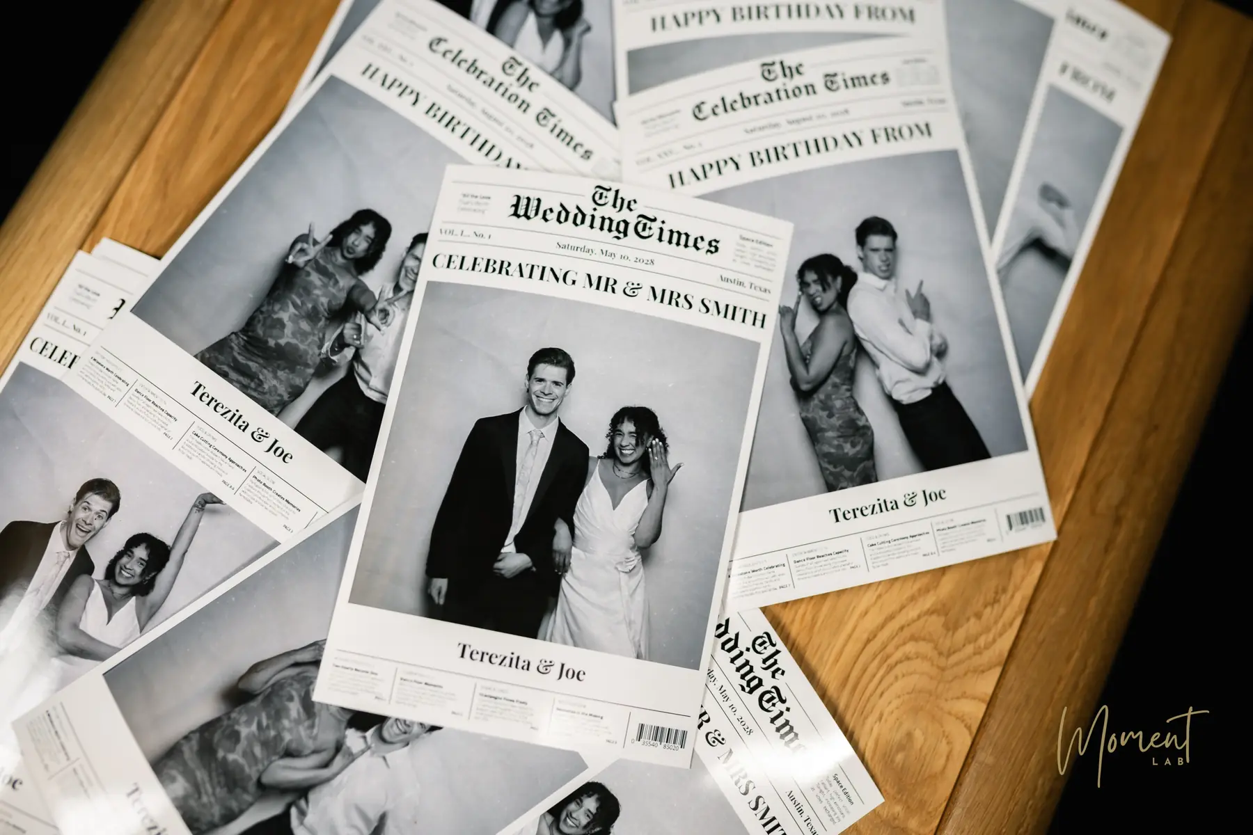 Printed newspaper-style photo booth front pages of wedding and birthday guests spread across a table
