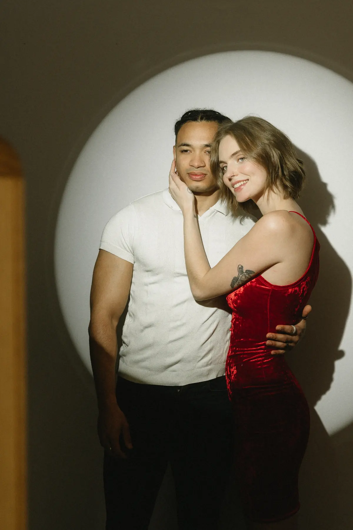 A couple embracing inside a circle of studio spotlight