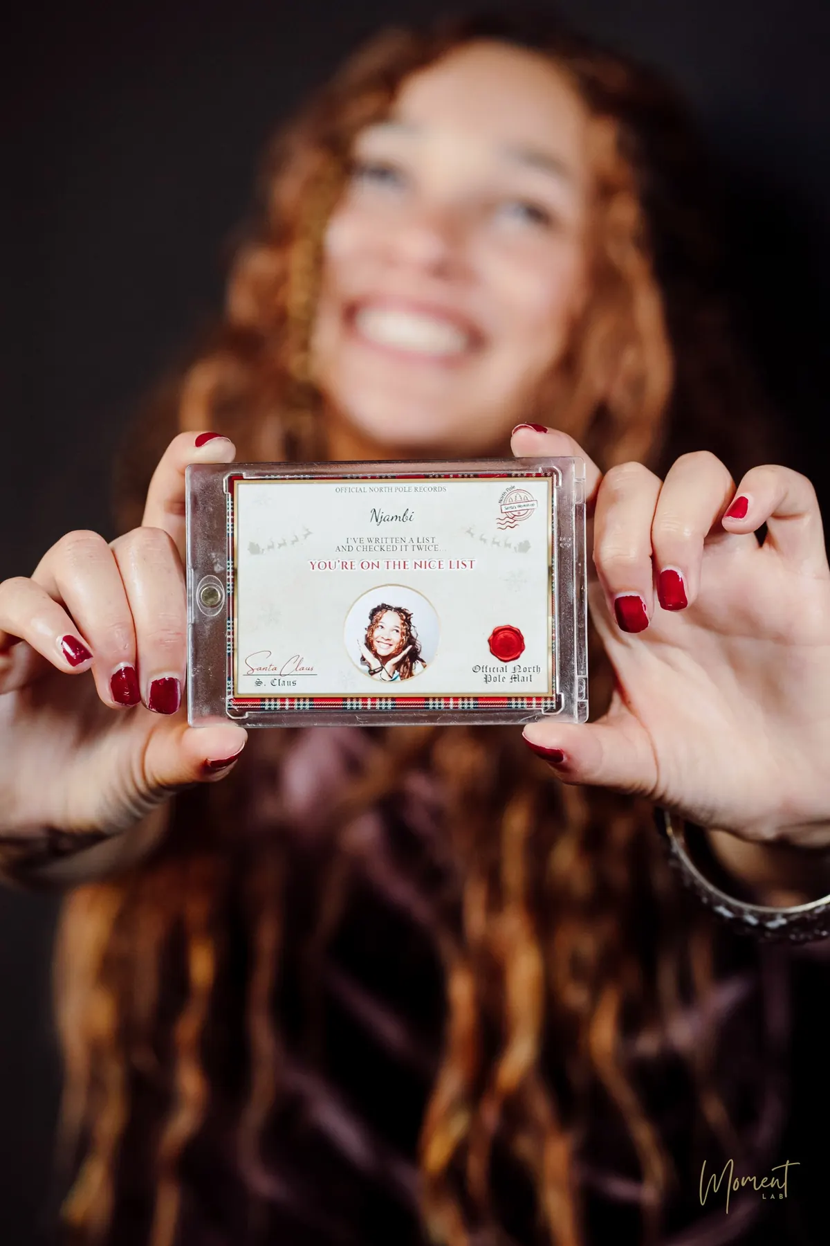 A personalised Nice List pass card with a guest's portrait, presented in a clear keepsake case