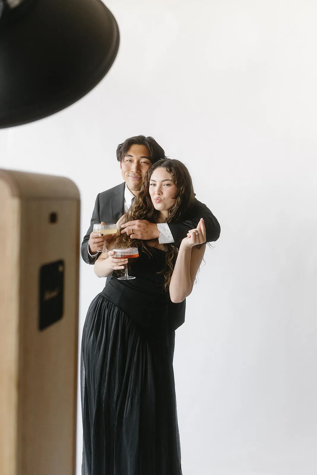 Wedding guests with cocktails posing at the photo booth
