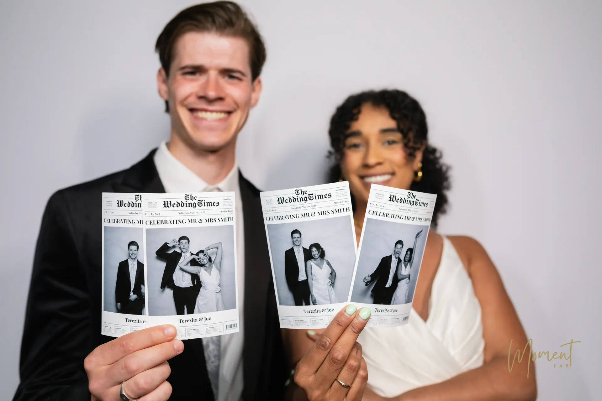 A wedding couple holding their newspaper-style photo booth prints
